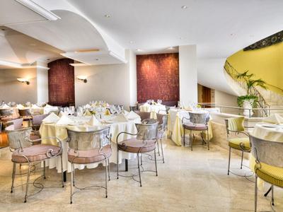 Elegant restaurant met ronde tafels, zachte stoelen en warme verlichting in een lichte ruimte.