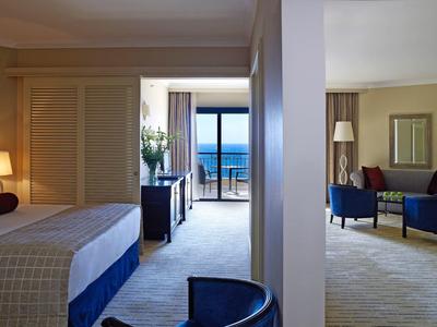 Ruime hotelsuite met aparte slaapkamer en woonkamer met uitzicht op de oceaan.