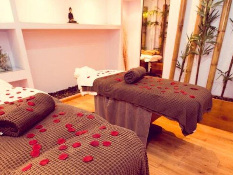 Gezellige spa-ruimte met twee massagetafels, bruine dekens, rozenblaadjes en bamboe decoraties.