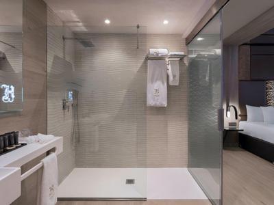 Nowoczesna łazienka z szklanym prysznicem i przyległą sypialnią.