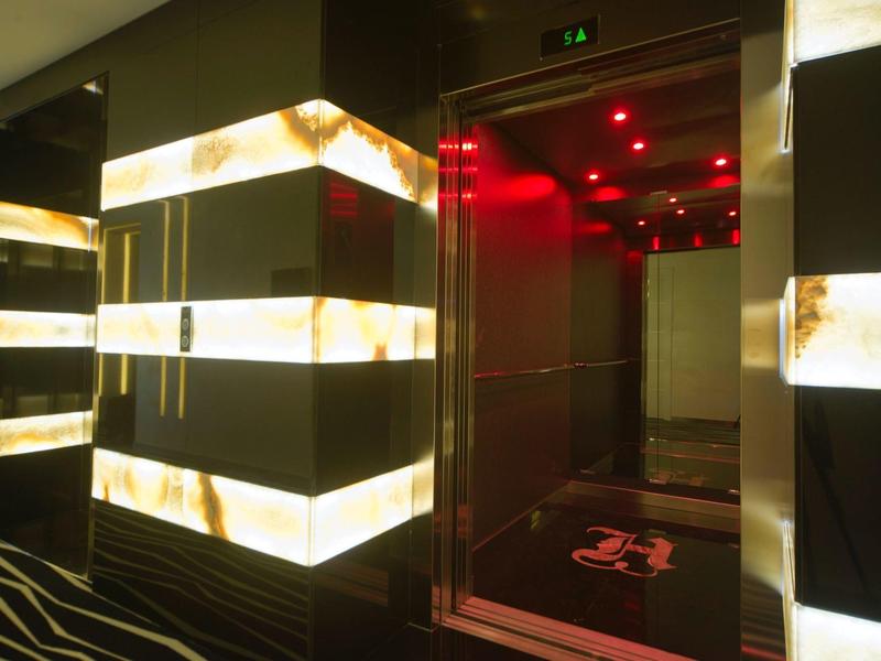 Nowoczesna winda z podświetlanymi ścianami i czerwoną iluminacją w hotelu.