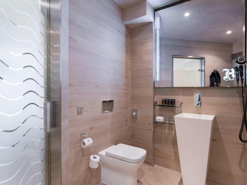 Nowoczesna łazienka z natryskiem bez brodzika, toaletą i wąską umywalką.