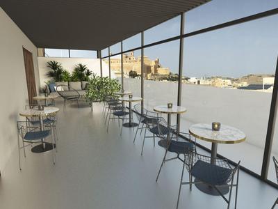 Nowoczesny balkon z szklaną balustradą, stolikami, krzesłami i roślinami z widokiem na miasto.