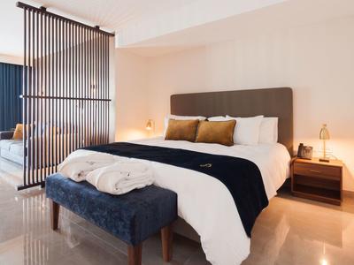 Moderně zařízená ložnice s velkou postelí, lavicí a nočními stolky s lampami.