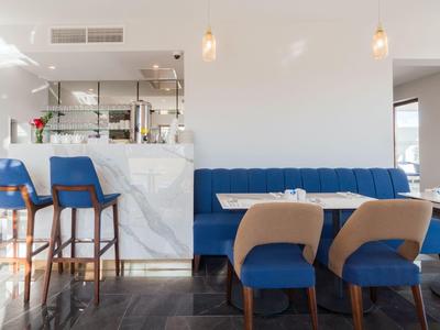 Nowoczesna przestrzeń hotelowa z niebieską sofą, beżowymi krzesłami i białym marmurowym barem