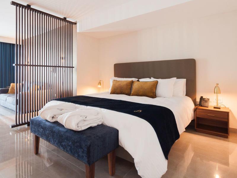 Moderně zařízená ložnice s velkou postelí, lavicí a nočními stolky s lampami.