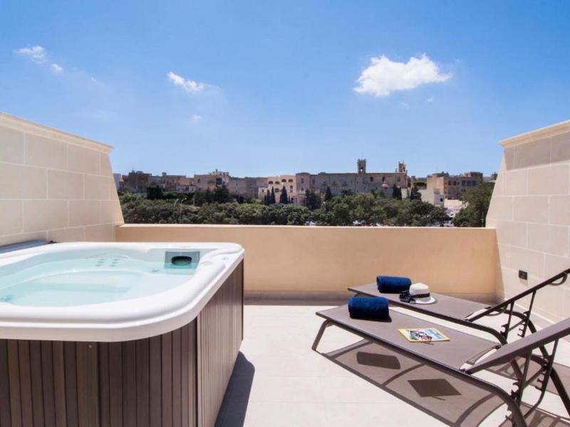 Terasa s vířivkou a lehátky s výhledem na město za jasné oblohy.