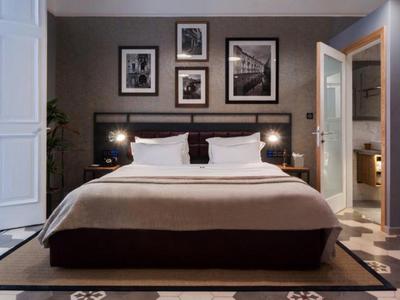 Nowoczesny pokój hotelowy z łóżkiem podwójnym, stolikami nocnymi i otwartą łazienką.