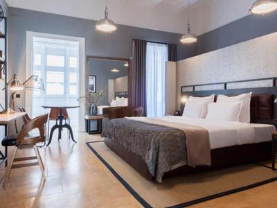 Nowoczesny pokój hotelowy z dużym łóżkiem, biurkiem i częścią wypoczynkową w dziennym świetle