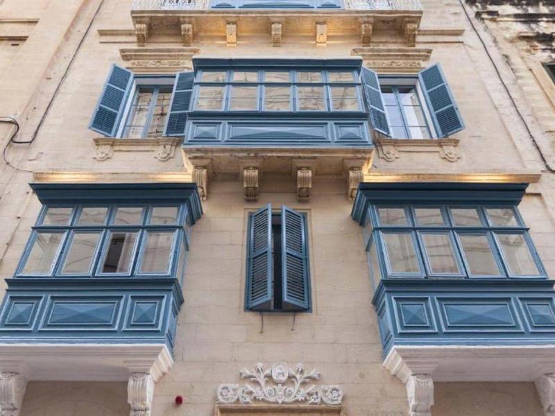 Zabytkowy budynek z niebieskimi wysuniętymi oknami i balkonem w europejskim pejzażu miejskim