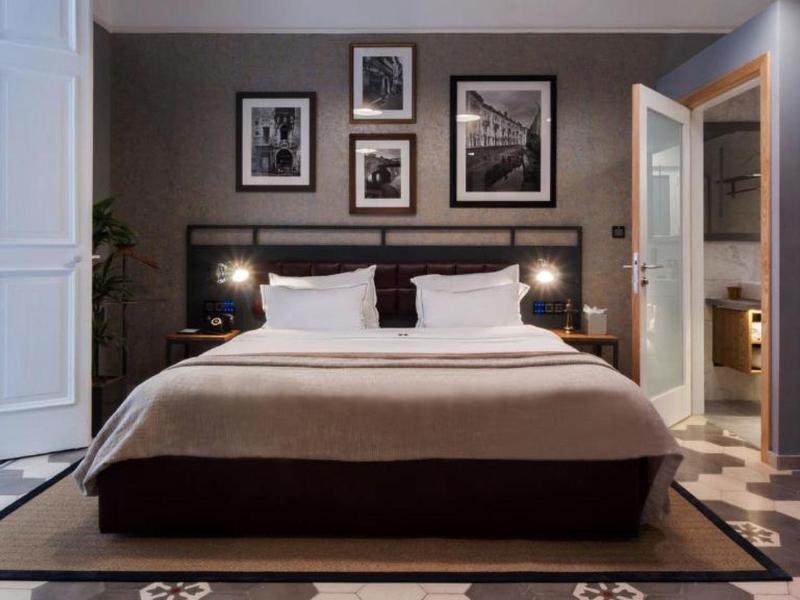 Nowoczesny pokój hotelowy z łóżkiem podwójnym, stolikami nocnymi i otwartą łazienką.