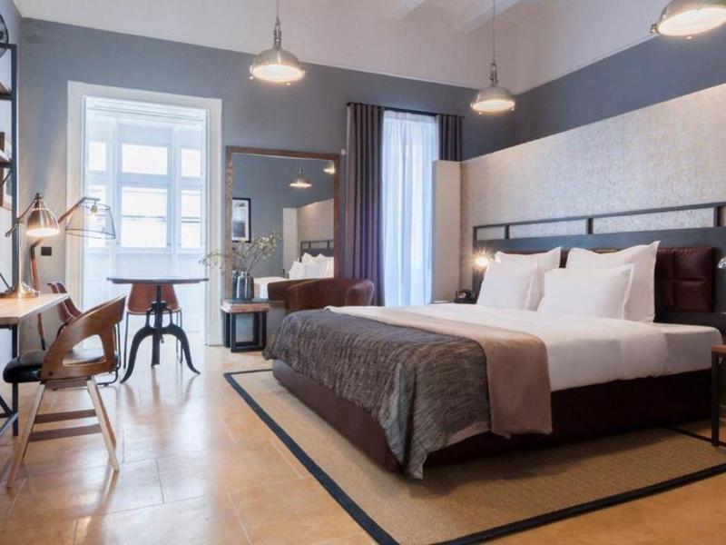 Nowoczesny pokój hotelowy z dużym łóżkiem, biurkiem i częścią wypoczynkową w dziennym świetle