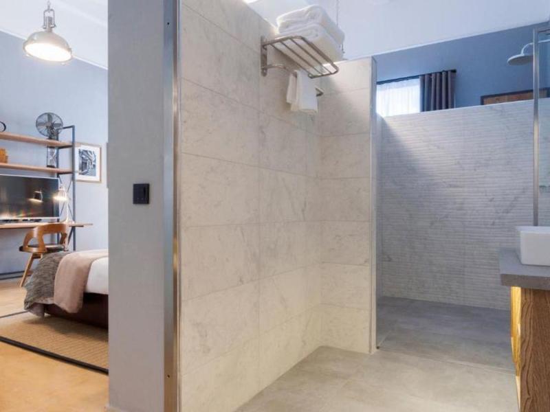 Nowoczesna otwarta przestrzeń mieszkalna z sypialnią i łazienką z tynkowanymi ścianami i minimalistycznym wyposażeniem.