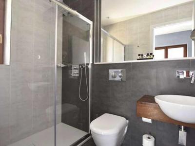 Modernes Badezimmer mit Glasdusche, Wandtoilette und Waschtisch im Hotelzimmer.
