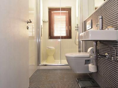 Modernes Badezimmer mit Toilette, Waschbecken und Dusche, schwarz-weiß gekachelt.