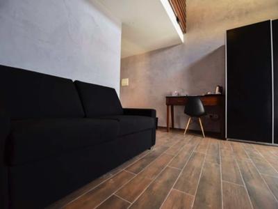 Modern eingerichtetes Hotelzimmer mit schwarzem Sofa, Schreibtisch und Holzfußboden.