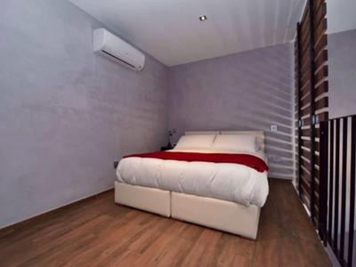 Modernes Schlafzimmer mit Doppelbett, Holzboden und minimalistischer Einrichtung in neutralen Tönen.