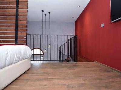Moderner Hotelzimmerbereich mit roter Wand, Holzboden und Treppenaufgang.