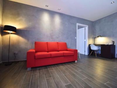 Modernes Wohnzimmer mit rotem Sofa, grauen Wänden und Holzfußboden in einem Hotelzimmer.