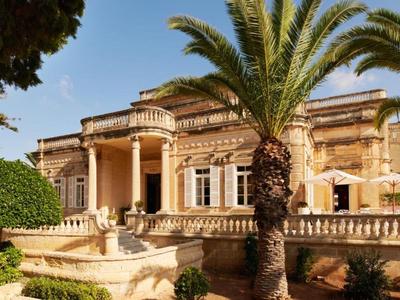 Historisch gebouw met zuilen, palmbomen en duidelijke lucht op de achtergrond