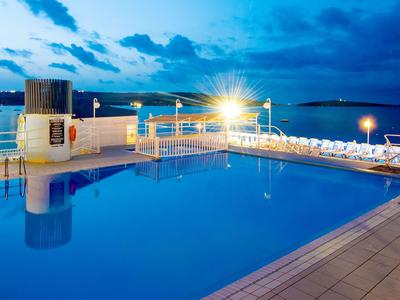 Beleuchteter Pool am Hotel mit Meerblick bei Dämmerung