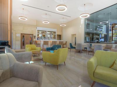 Moderne Hotellobby mit bequemen Sesseln, hellem Holz und dekorativer Beleuchtung.