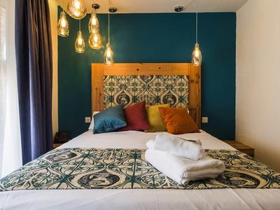 Modern eingerichtetes Hotelzimmer mit Bett, gemustertem Kopfteilstoff und mehreren Kissen.