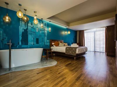 Modernes Hotelzimmer mit Doppelbett, Badewanne und großem Fenster mit Vorhängen.