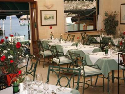 Ein ruhiger, stilvoll gedeckter Außenbereich eines Restaurants mit grünen Tischdecken und roten Blumen.