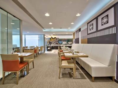 Área de comedor moderna del hotel con mesas, sillas y ventanas panorámicas con vista al mar.