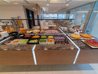 Bufet z szerokim wyborem świeżych owoców, warzyw i wypieków w nowoczesnej jadalni.