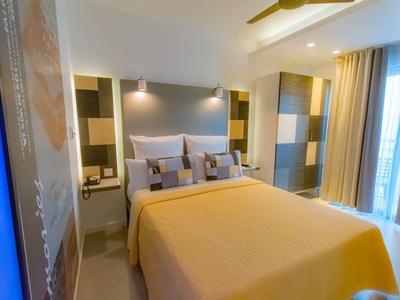 Habitación de hotel moderna con cama grande, colores cálidos y balcón con cortinas