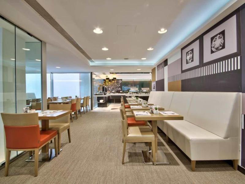 Nowoczesna restauracja hotelowa z białymi ławkami, drewnianymi stołami i widokiem na ocean.