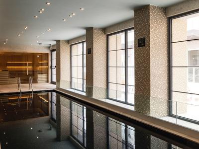 Indoor pool in a hotel with large windows and modern lighting.