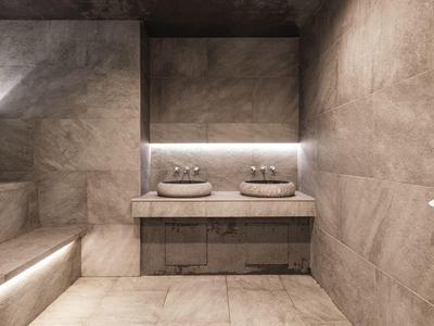 Modern spa room with stone walls, built-in bench, and double stone sinks on a countertop.