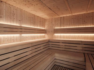 Cozy wooden sauna with tiered benches and warm, recessed lighting along the walls.