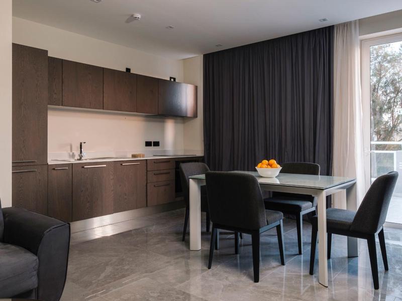 Modern hotel dining area with dark furniture and large window with curtain.