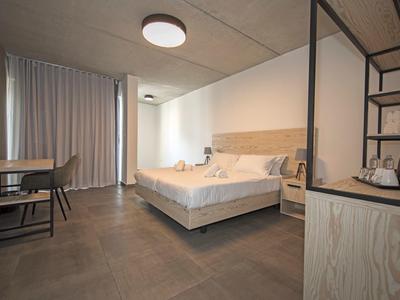 Chambre d'hôtel moderne avec grand lit, bureau et rideaux clairs.