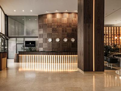 Moderne hotelreceptie met verlichte balie en houten wanddetails.