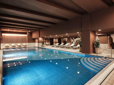 Modernes Hallenbad mit blau gekacheltem Becken und Liegen in einem luxuriösen Spa-Bereich.