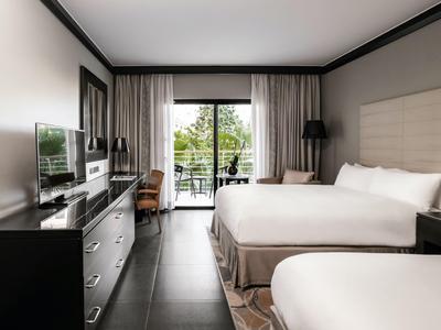 Modernes Hotelzimmer mit zwei Betten, Fernseher und Balkon mit Grünblick