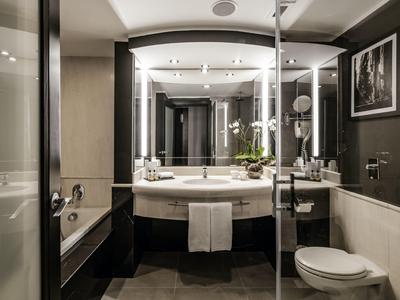 Moderner Badbereich mit Waschtisch, Badewanne, Toilette und stilvoller Beleuchtung.