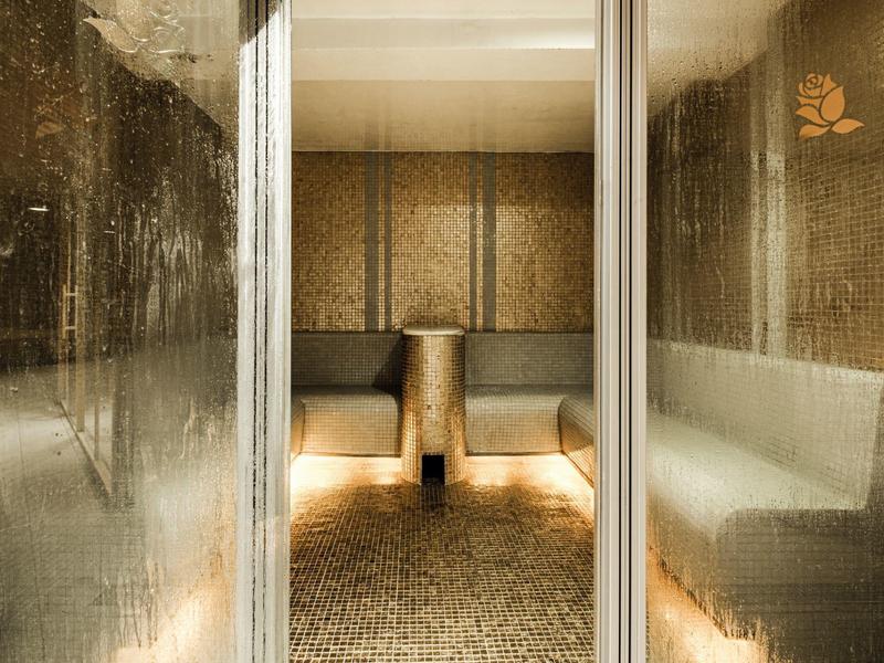 Saunaraum mit gedämpftem Licht, gläserner Tür und bequemen Bänken an den Wänden