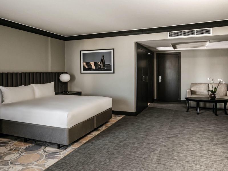 Modern eingerichtetes Hotelzimmer mit großem Bett und gemütlichem Sitzbereich