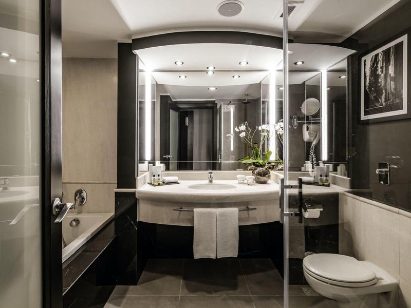 Moderner Badbereich mit Waschtisch, Badewanne, Toilette und stilvoller Beleuchtung.