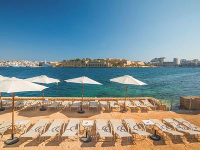 Wybrzeże z leżakami i parasolami nad niebieskim morzem pod jasnym niebem.