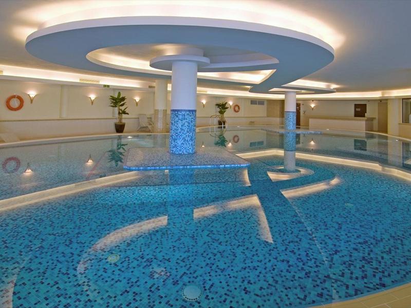 Basen kryty z niebiesko wyłożonymi ścianami i sufitem z oświetleniem pośrednim.