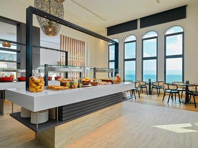 Helles, modernes Café mit großem Buffet und Panoramafenstern mit Blick auf das Meer.