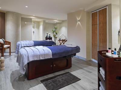 Gemütlicher Behandlungsraum mit Massageliege, gedämpftem Licht und entspannender Dekoration.