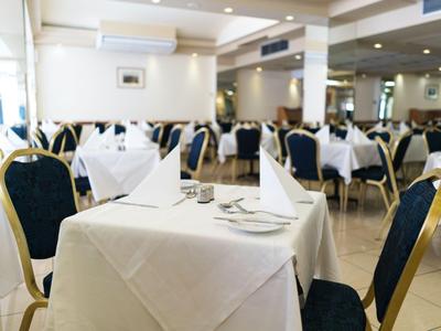 Ristorante elegante con tovaglie bianche e sedie blu-oro in una stanza luminosa.